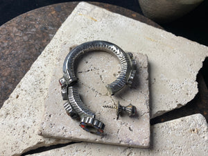 Very high grade silver, women's hinged cuff from Afghanistan. Hollow construction with a hexagon profile, this bracelet is hinged and features several florets of silver set with glass stones in red, blue and green, and a high profile reverse screw fastening and two stylised half opium poppies. 19th century