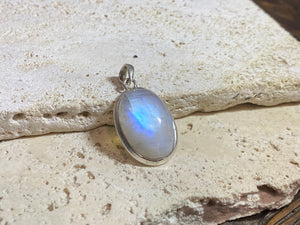 Oval high cut rainbow moonstone pendant set in sterling silver with a generous flexible bail to take a large chain or cord. A high quality stone with blue colour and fire.