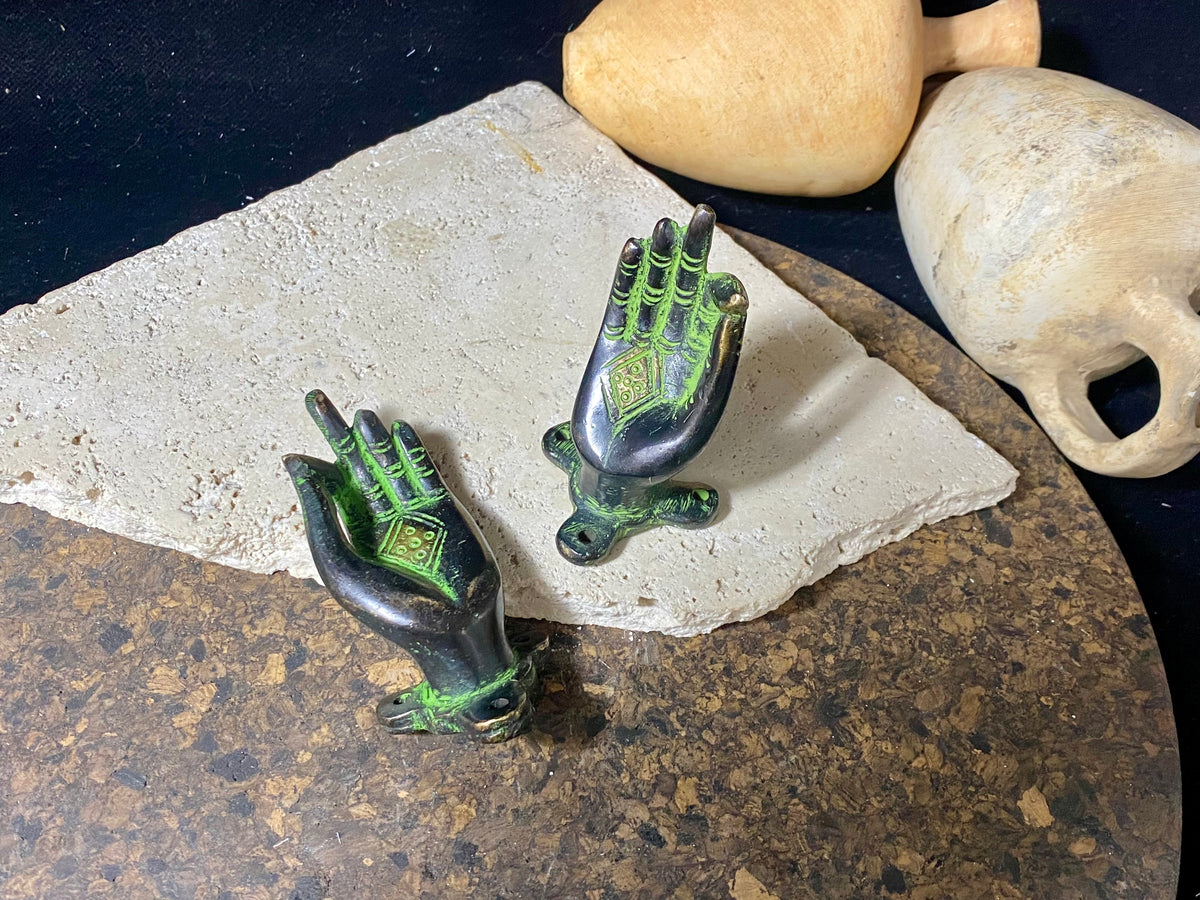 Bronze hands of Buddha that can be oriented up, sideways or downward facing. Hand cast from solid brass with a diamond shaped lotus viswa vajra in the centre of each palm and highlighted with a light green pigment. The hands have three attachment points. These make beautiful door, cupboard or drawer handles, and also work as pegs. Price is for one pair. Measurements: 9 cm (3.4") length
