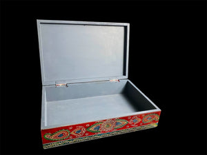 This charmingly painted box features one very large compartment and features a lid that is raised via hinges and. small brass knob as handle. The roominess of the box means it is perfect for holding everything from trinkets to watches, jewellery and keys. A lovely, hand painted piece of craftsmanship from Rajasthan, India.

Measurements: width 38, depth 25 cm, height 10 cm