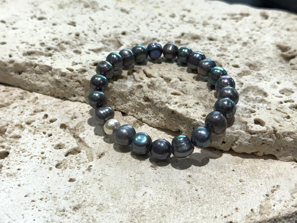 A simple and elegant bracelet of large black freshwater pearls and a single sterling silver bead. Elasticised stringing for a seamless look.