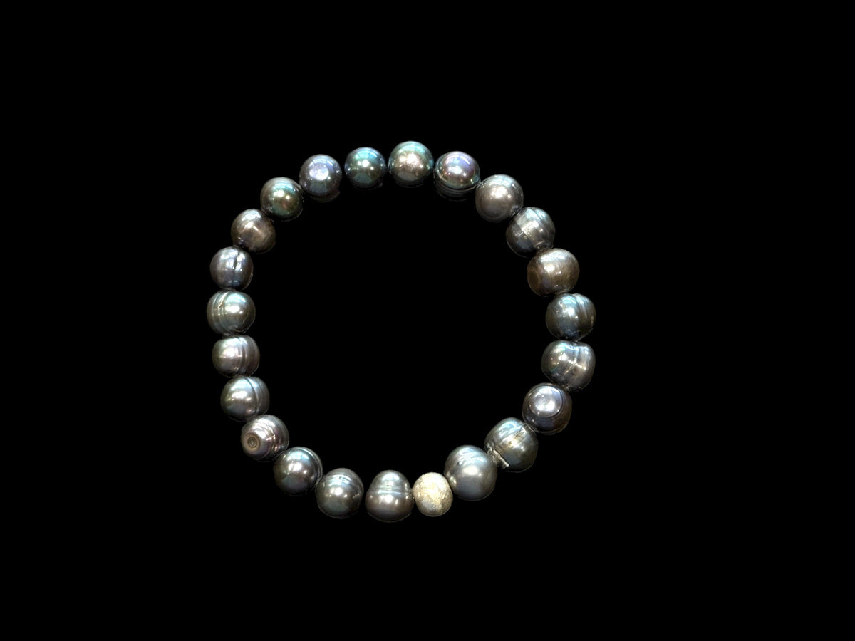 A simple and elegant bracelet of large black freshwater pearls and a single sterling silver bead. Elasticised stringing for a seamless look.
