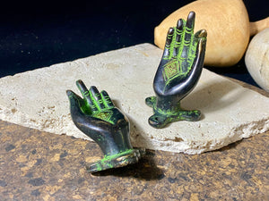 Bronze hands of Buddha that can be oriented up, sideways or downward facing. Hand cast from solid brass with a diamond shaped lotus viswa vajra in the centre of each palm and highlighted with a light green pigment. The hands have three attachment points. These make beautiful door, cupboard or drawer handles, and also work as pegs. Price is for one pair. Measurements: 9 cm (3.4") length