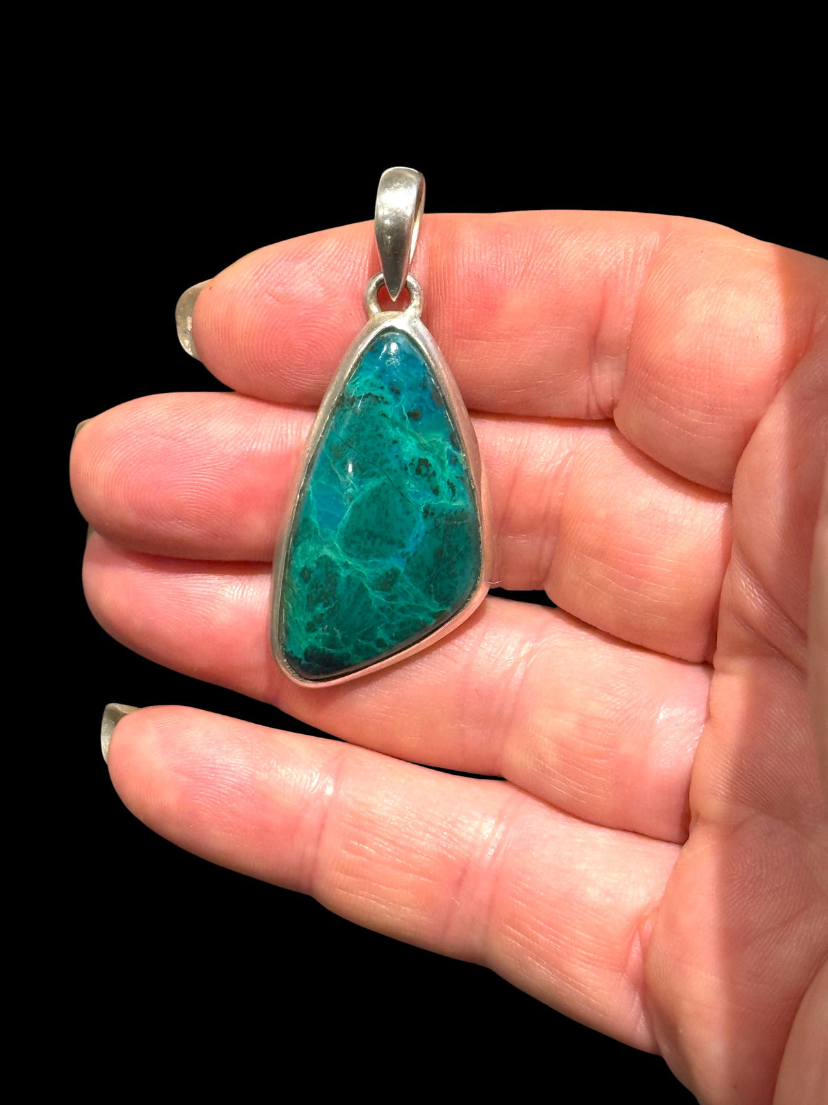 Blue green chrysocolla pendant set off by a sterling silver bezel and bail. Height 5 cm, 2.1 cm at widest point
