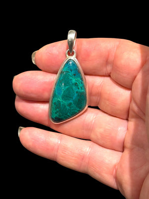 Blue green chrysocolla pendant set off by a sterling silver bezel and bail. Height 5 cm, 2.1 cm at widest point