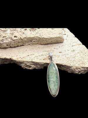Long emerald pendant, frosted light green colour, facet cut, set in a shadow box mounting of sterling silver. Large bail. Height 6 cm, width 1.7 cm.