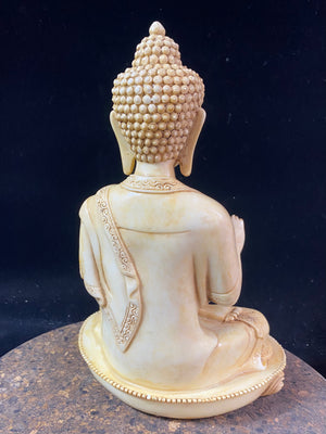 Amoghshiddhi Buddha cast in cream coloured resin. His right hand is held up facing outwards in the gesture of protection of fearlessness while his left hand sits in his lap in the gesture of meditation. Cast in solid resin, then hand finished to a very high standard. Measurements: height 26 cm, width 18 cm, depth 12 cm