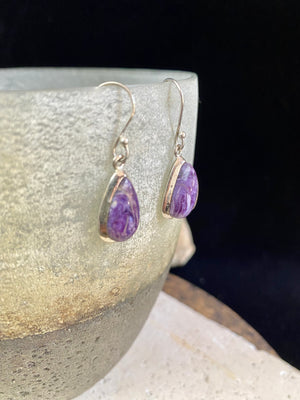 These lustrous charoite earrings are set off by a sterling silver bezel, topped by sterling silver shepherd hooks.  Measurements: 3.5 cm height including hooks, 1 cm at widest point 