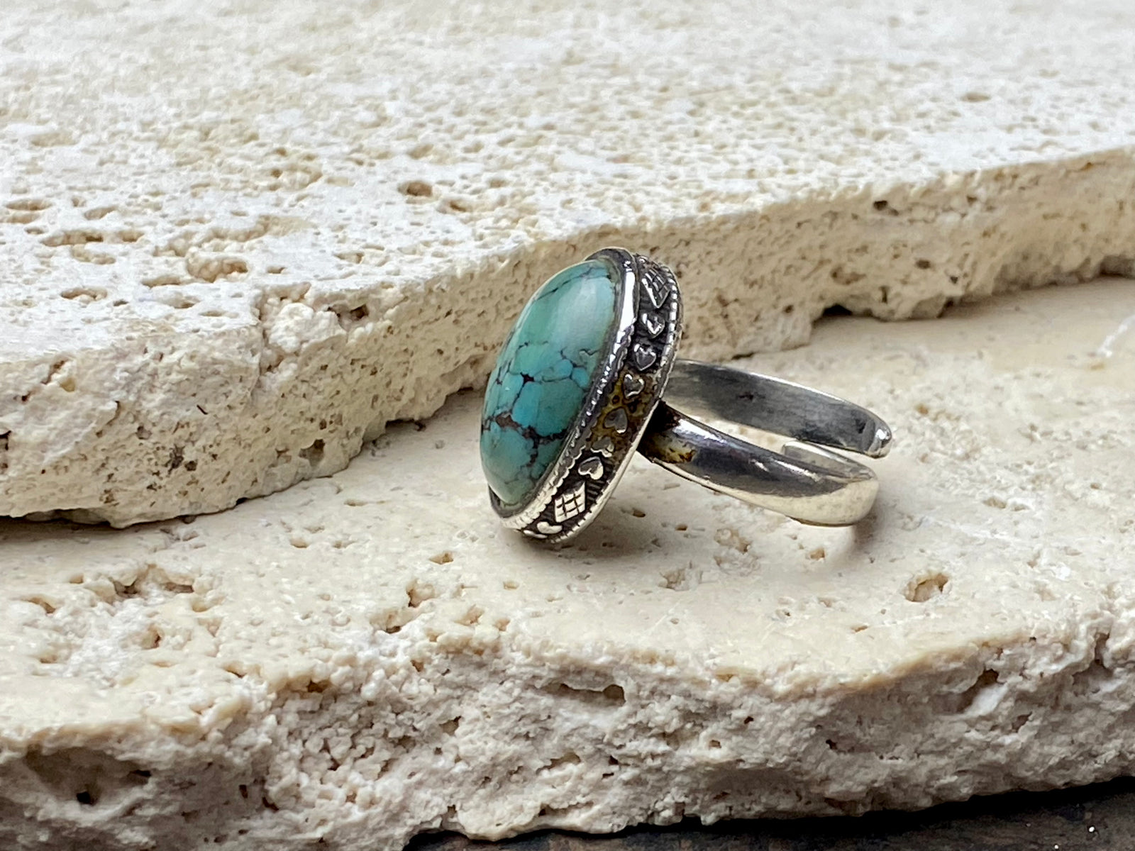 This simple ring features a large antique cabochon turquoise stone, set in a simple patterned silver bezel, with an adjustable ring band. As is the case with many of the rings we are currently buying, the stone is old and has been reset into a new silver band.  Measurements:  Ring face 2 x 1.5 cm Inner diameter 16.5 mm | Size 6 , however the adjustable band will fit any finger sized 5 -7