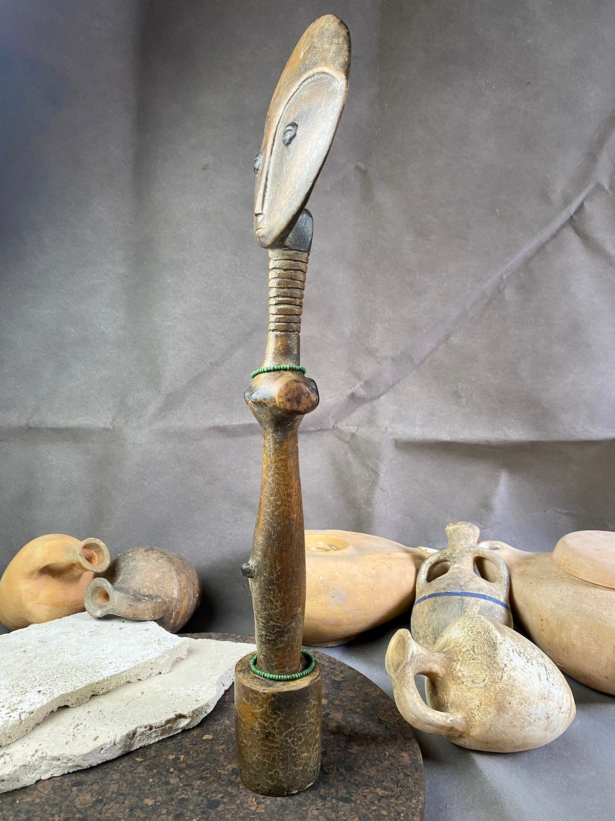 Late 20th Century vintage figure is carved from fine-grained wood, with a natural patina worn smooth with handling. She wears carved neck rings as well as beaded decoration, and a stylised pack on her back. This doll has an well carve face, with other features hinted at rather than explicitly carved. Height 43cm, width at head 11.5 cm.