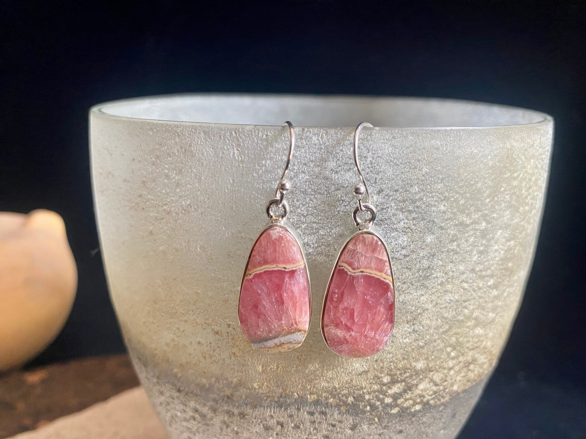 The most beautiful rhodochrosite we've ever seen. Every piece tells a story, and all earring pairs feature perfectly matched stones set in sterling silver bezels. Finished with sterling silver hooks.