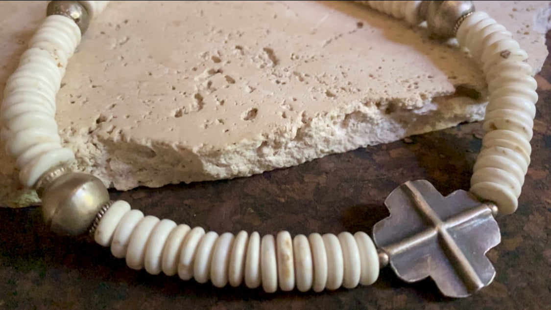A mid-length white howlite and silver necklace crafted crafted from natural heshi cut beads, with a handmade sterling silver cross centrepiece and antique Indian silver beads. Finished with sterling silver ends and hook clasp. Total length 51.8 cm, pendant 2.5 cm diameter