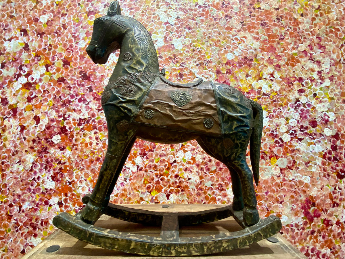 Antique Indian rocking horse. Covered entirely in sheets of embossed brass and copper sheet with floral and ornamental plaques, strap work and highly embossed decoration. Hardwood Early 20th century, southern India. Measurements: height to ear 52 cm, length 40.5 cm, width 13.5 cm.