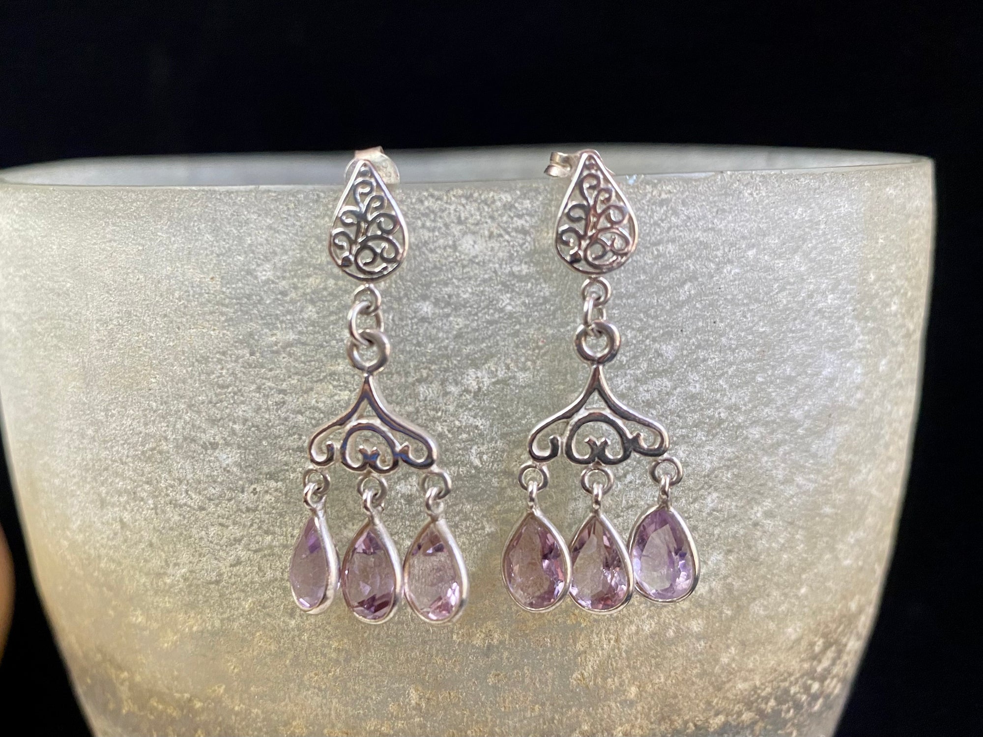 Amethyst chandelier earrings set in filigree silver with a post and butterfly back attachment. The matching light purple teardrop shape amethyst stones are facet cut to display their excellent quality and sparkle as they move en tremblant.