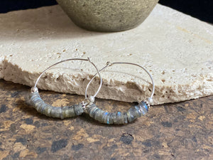 Stunning, large labradorite hoop earrings, crafted from flat labradorite stones that are facet cut on every side to show off their stunning fire and lustre. Sterling silver hoops complete the look. Measurements: 5 cm diameter