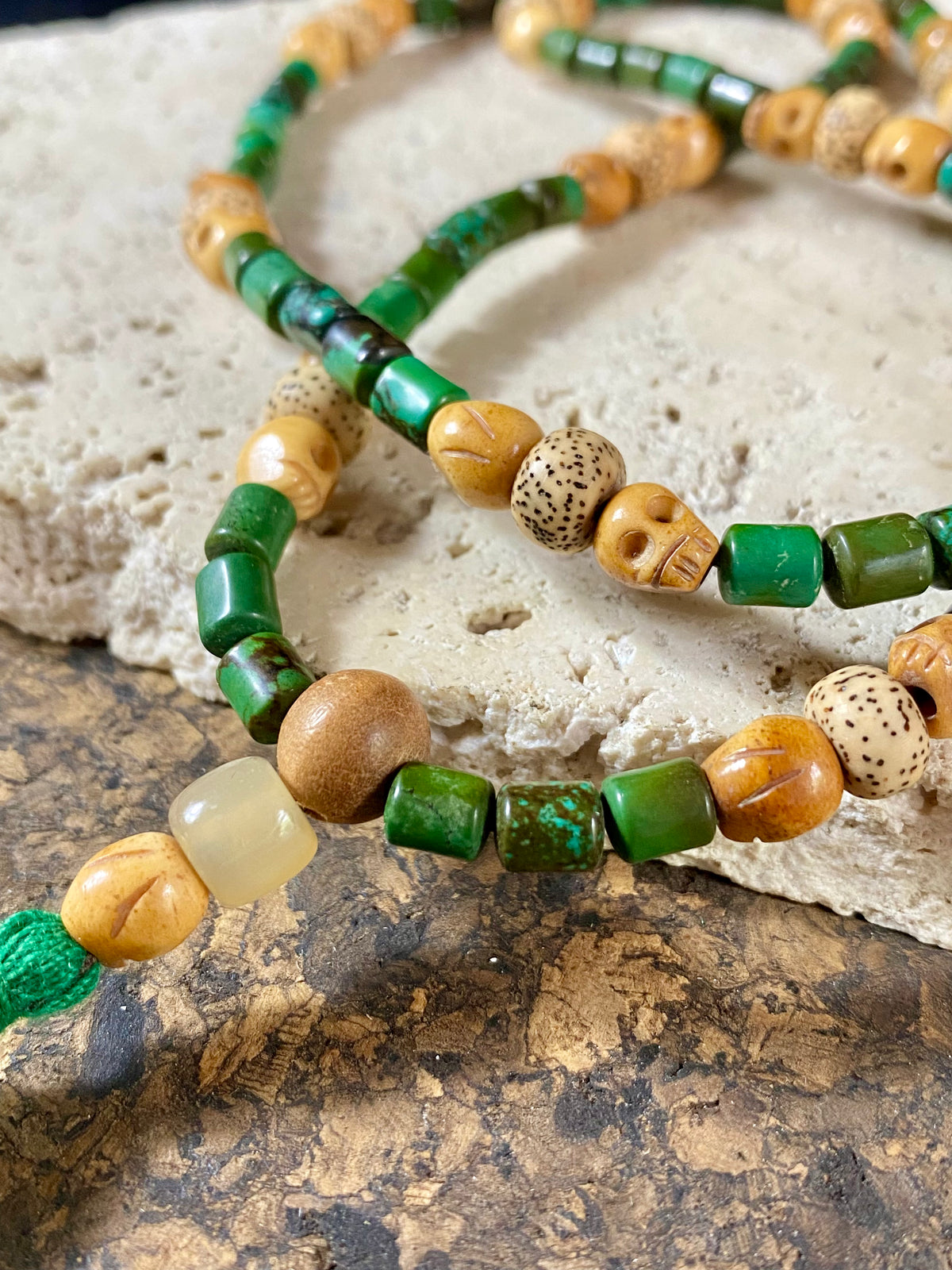 Our luxurious Buddhist mala contains 108 beads and has a beautifully organic look and feel. It's made from dark green turquoise beads, skull carved yak bone beads and lotus root beads, all finished with a sandalwood guru bead and a yak horn bead. Finished with a dark green tassel.