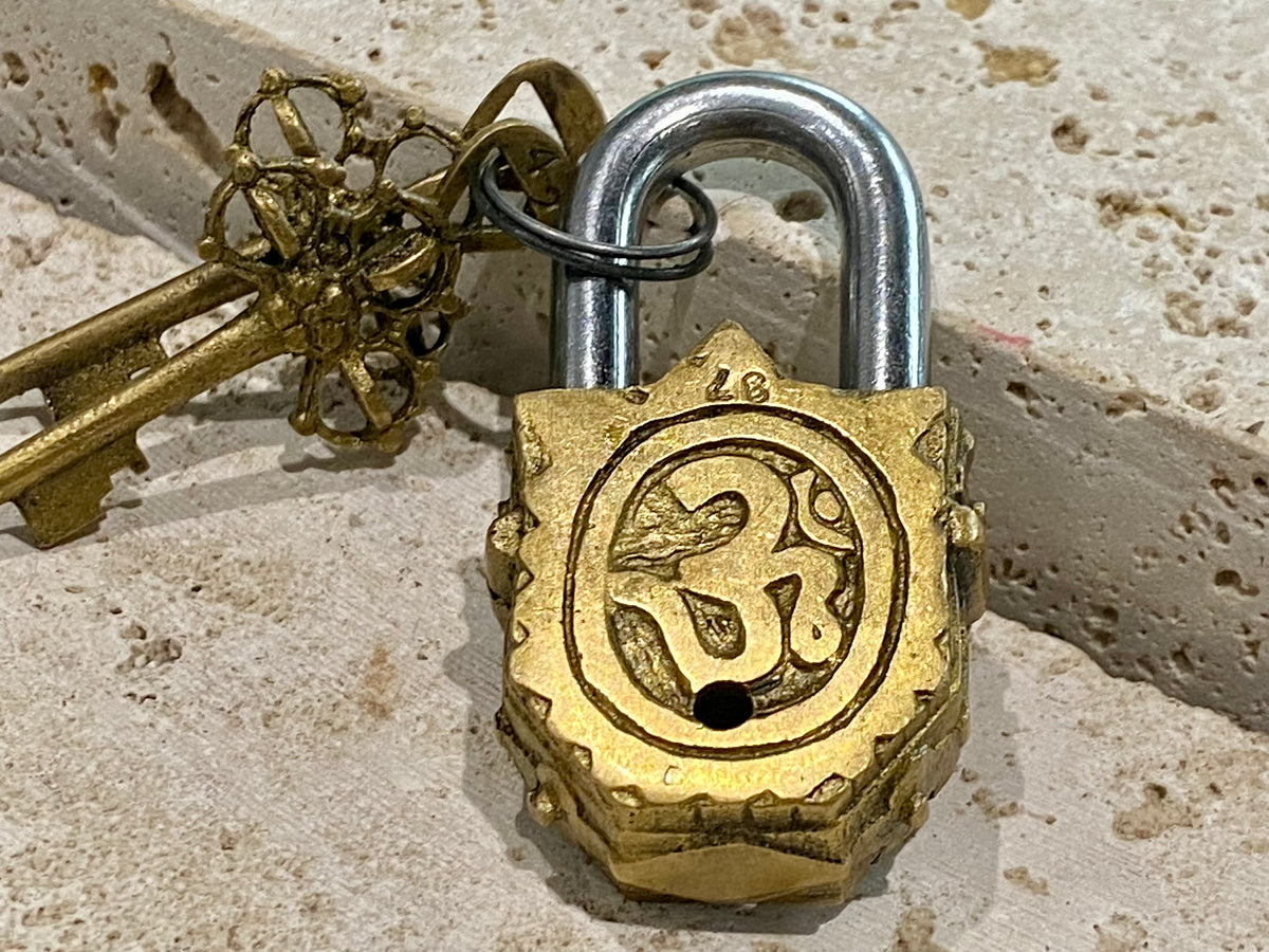 Small brass Indian deity padlocks embossed with the image of Ganesh or Laxmi. to keep your possessions safe and blessed. On the back is the Om, powerful Buddhist protective symbol. Two keys provided with every lock. On the top of each is the viswa vajra, a Buddhist protective symbol. Measurements: height 6.5 cm, width 3 cm, depth 1.5 cm
