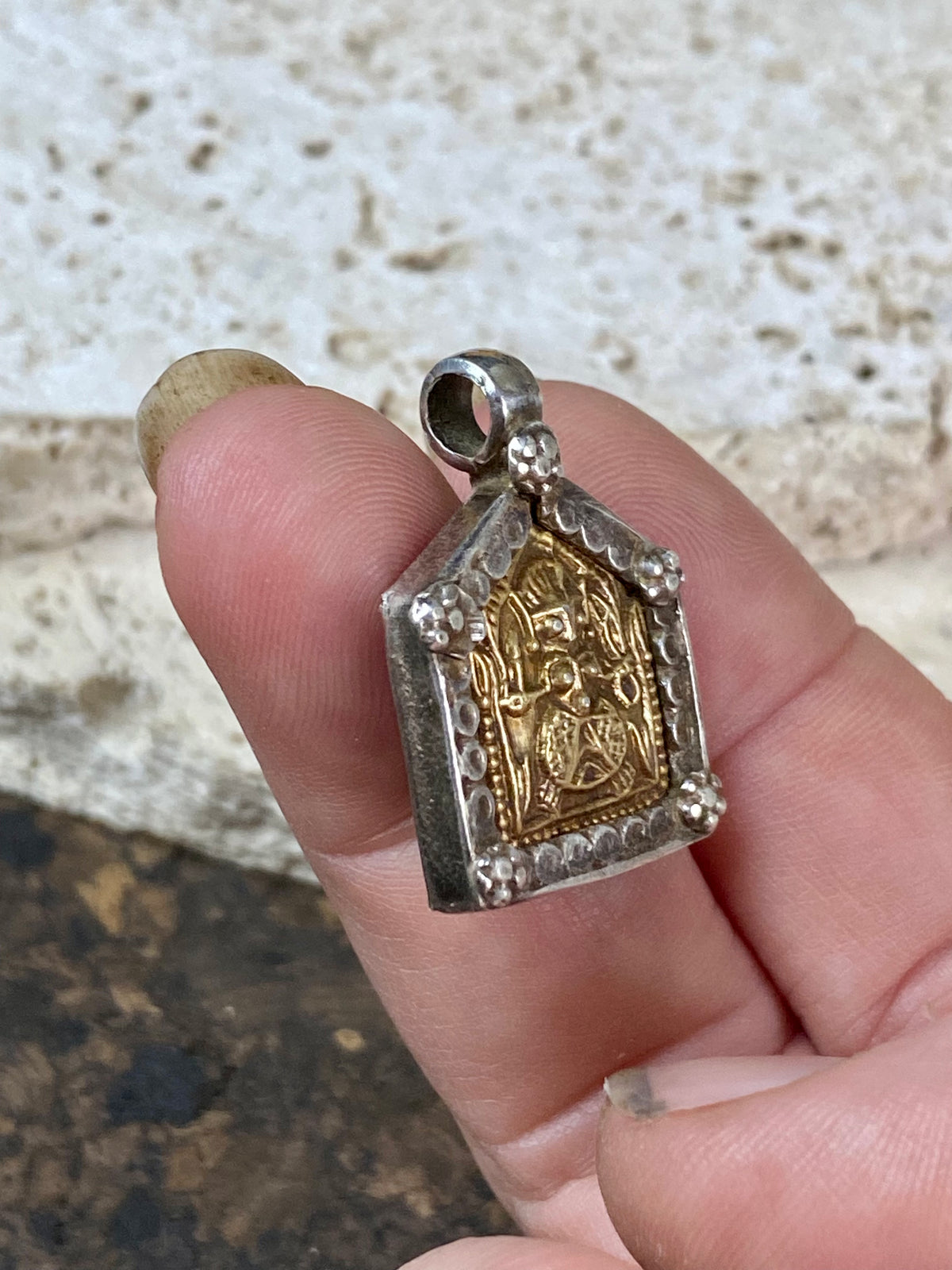 antique tribal amulet depicting Durga in Kali form. High grade silver with a 22 kt gold finish over the amulet face. Early 20th century or earlier. This is a unique amulet in its depiction of the goddess in tribal headdress and its use of silver and gold.  Height 2.7 cm including bail, width 2 cm