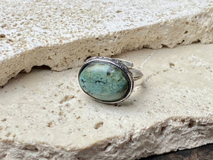 This simple ring features a large antique cabochon turquoise stone, set in a simple patterned silver bezel, with an adjustable ring band. As is the case with many of the rings we are currently buying, the stone is old and has been reset into a new silver band.  Measurements:  Ring face 2 x 1.5 cm Inner diameter 16.5 mm | Size 6 , however the adjustable band will fit any finger sized 5 -7