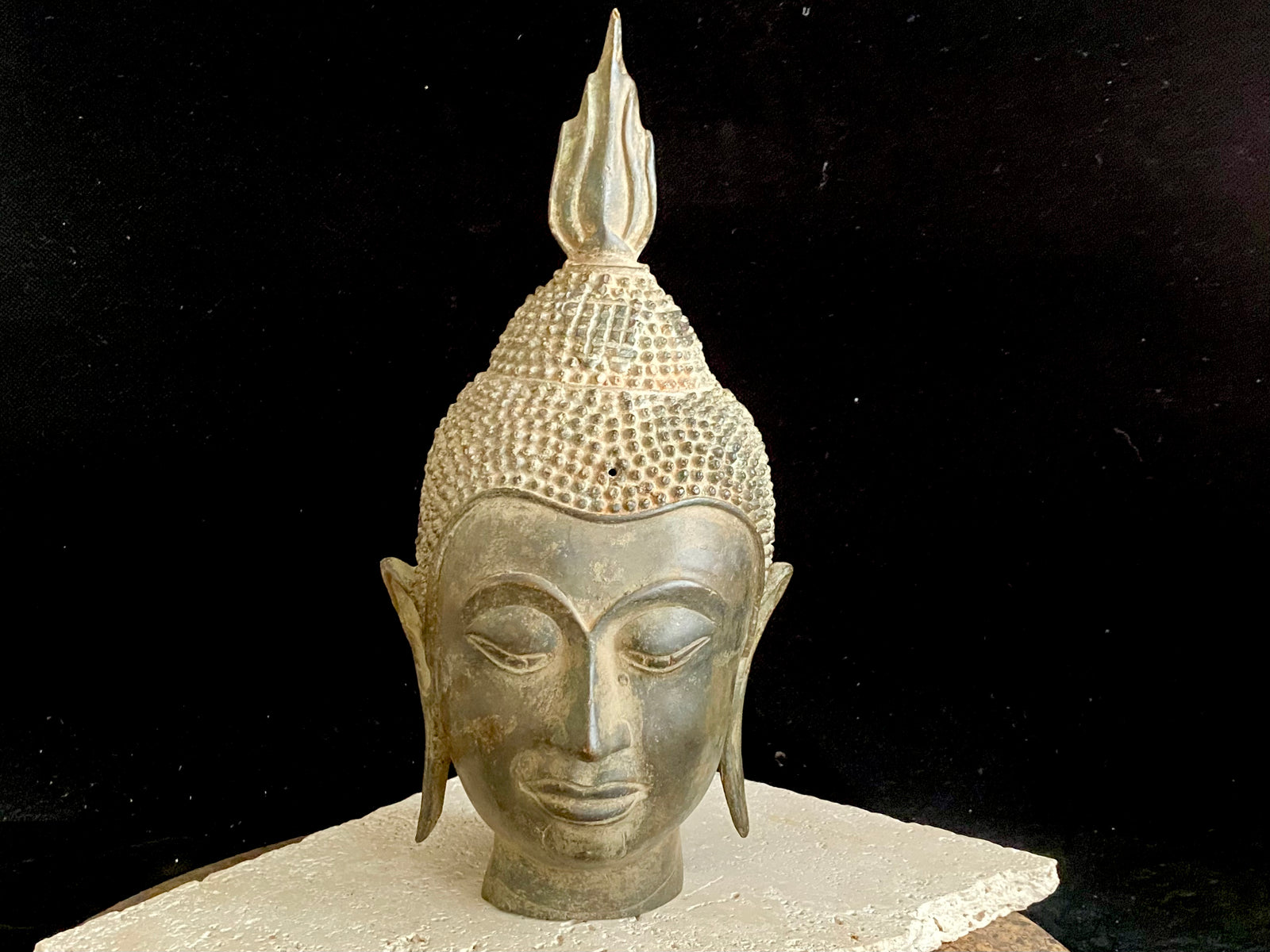 Thai Buddha head. Serene expression, hair topped with the flamed Ushnisha. Sukhothai style, bronze, mid 20th century. A softly contoured face with the bow shaped lips, prominent ears, arched eyebrows and aristocratic features typical of this style of work. Measurements: height 25 cm, width 11 cm