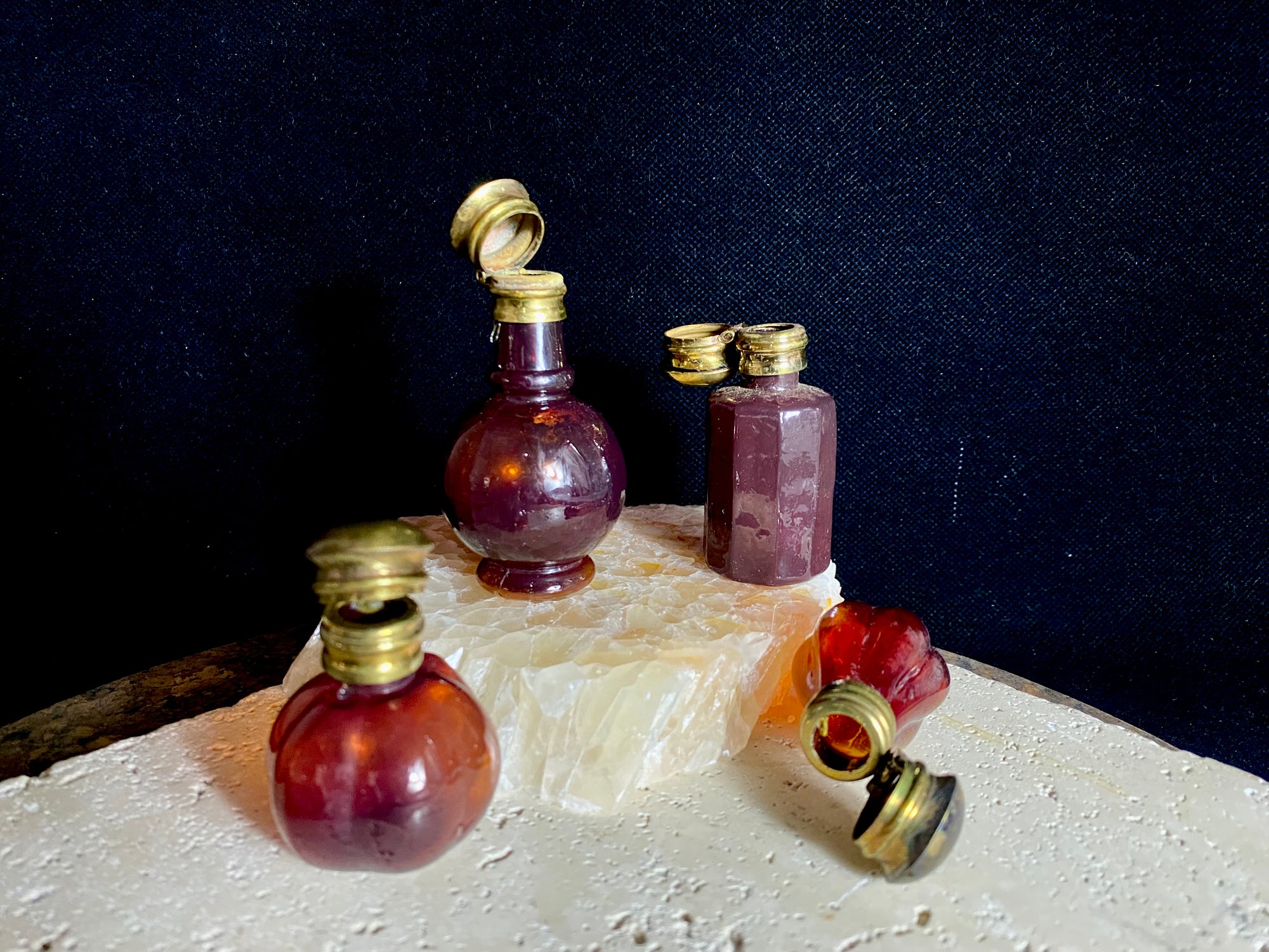 Small cranberry glass perfume bottles with hinged flip top brass lids.&nbsp;