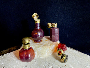 Small cranberry glass perfume bottles with hinged flip top brass lids.&nbsp;