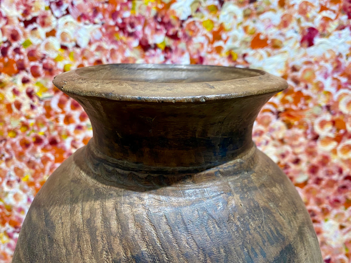 These gracefully shaped pots were used to store lassi, oil, milk, water and grain. This large example comes from northern India and is carved from solid hardwood, in this case most likely teak. Mid 20th century or earlier. slight decoration around the neck and mouth. Repair to the base. Measurements: diameter 22 cm, height 28 cm