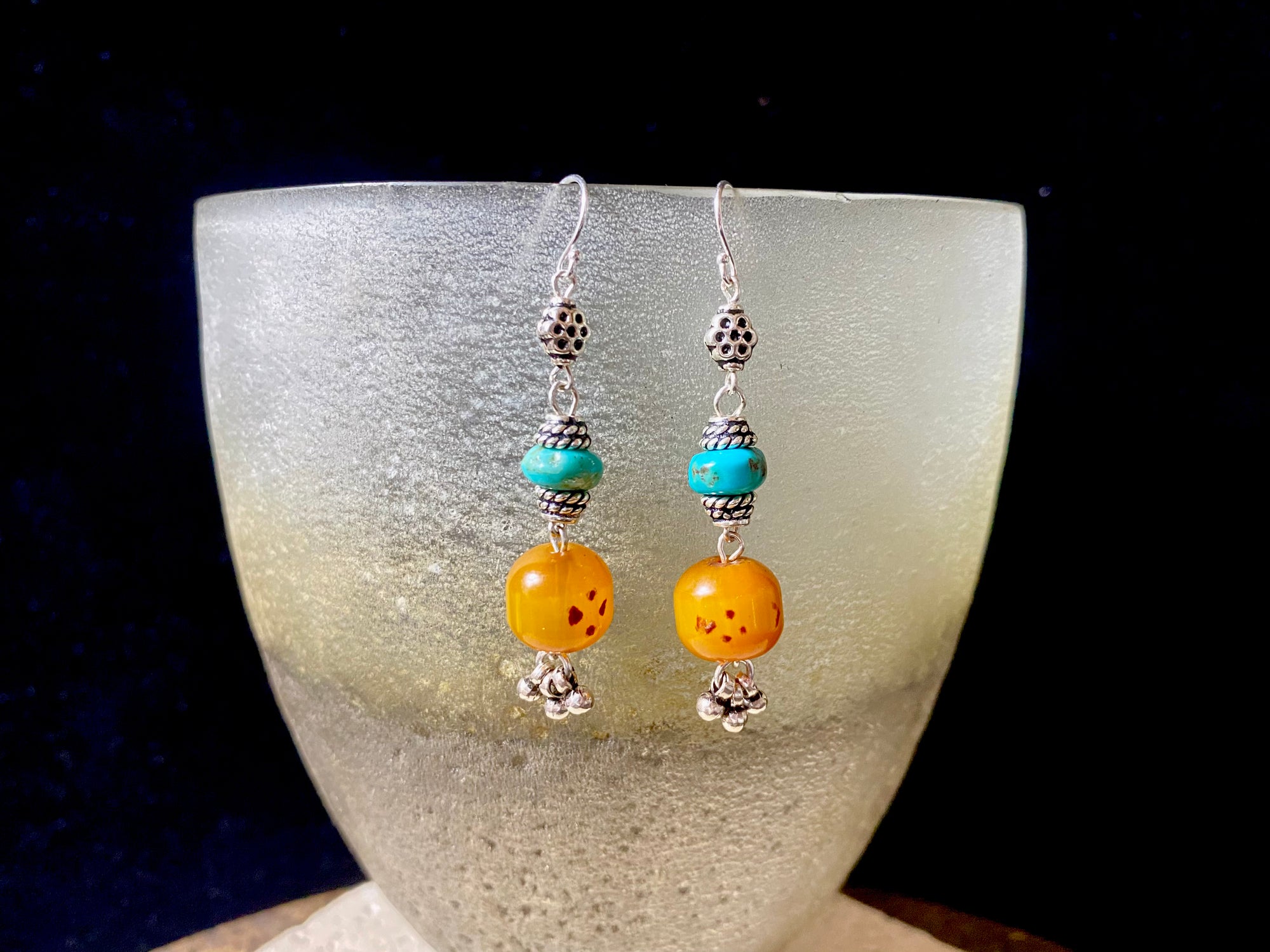 These exotic earrings were created from vintage copal amber beads topped with Arizona turquoise and handmade sterling silver beads, finished with sterling silver hooks.These are a one-off earring design that are very light and easy to wear. Length 5.8 cm including hook