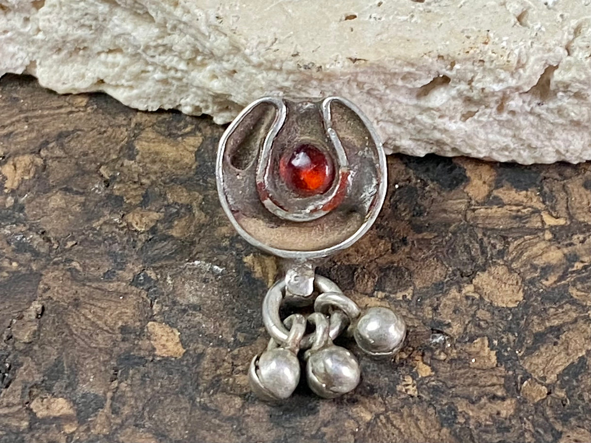 This old amulet represents the female principal through its depiction of the yoni or gauri-patta. The channel once held enamel and the central stone has been replaced at some time recently. Early 20th century. High grade silver, from northern India. This is a beautiful, old amulet with history. Height 2.5 cm including dangles, height of pendant 1.4 cm, width 1.3 cm