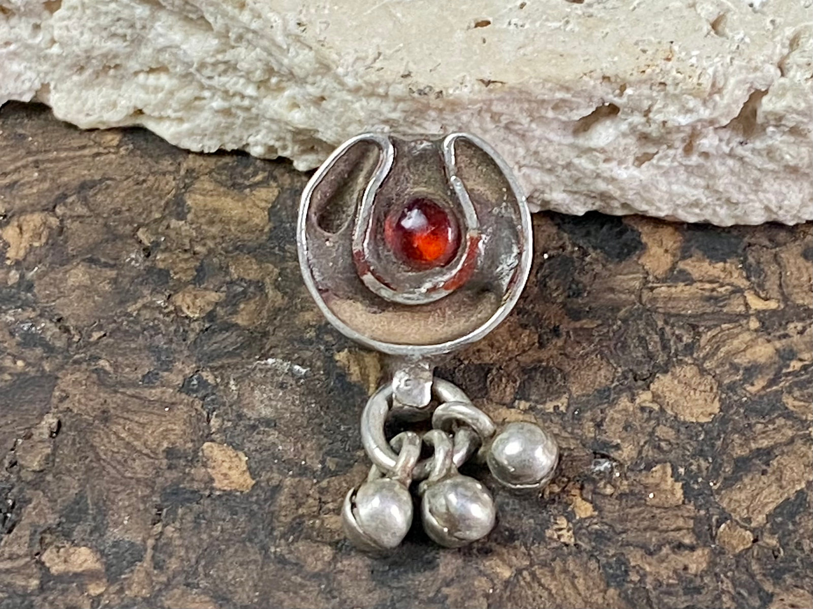 This old amulet represents the female principal through its depiction of the yoni or gauri-patta. The channel once held enamel and the central stone has been replaced at some time recently. Early 20th century. High grade silver, from northern India. This is a beautiful, old amulet with history. Height 2.5 cm including dangles, height of pendant 1.4 cm, width 1.3 cm