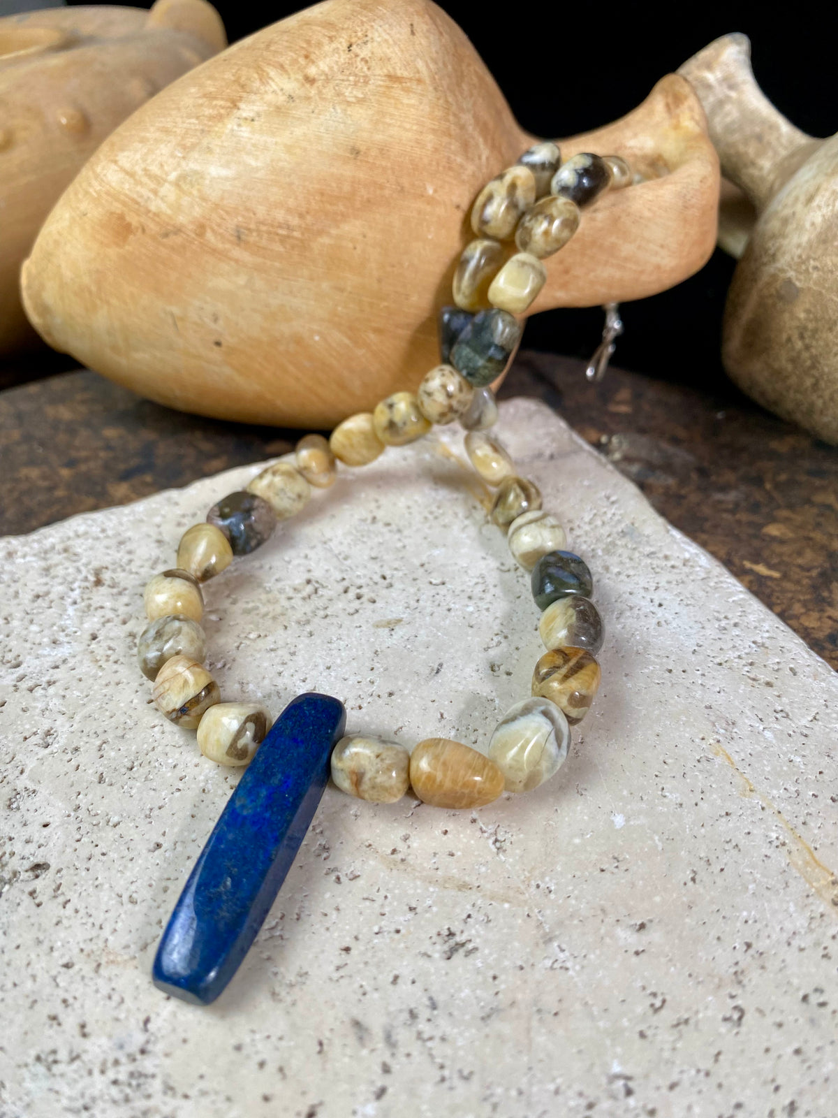 A necklace crafted from zebradorite  jasper with highlight beads of grey opal and a central hand carved pendant of Afghani lapis lazuli. Finished with sterling silver beads and hook clasp. Our necklace can be worn by either men or women  Length 42.4 cm 