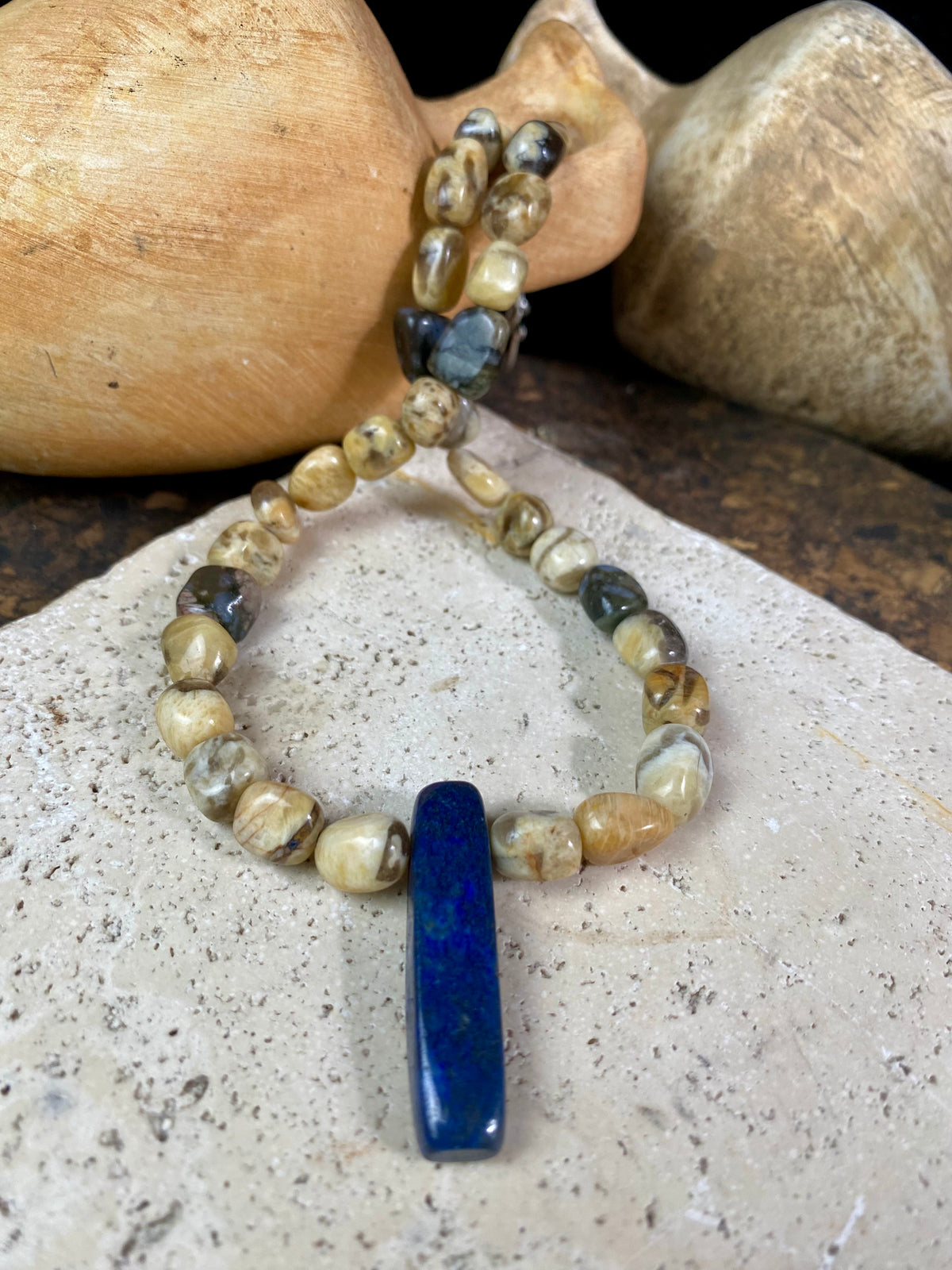 A necklace crafted from zebradorite  jasper with highlight beads of grey opal and a central hand carved pendant of Afghani lapis lazuli. Finished with sterling silver beads and hook clasp. Our necklace can be worn by either men or women  Length 42.4 cm 
