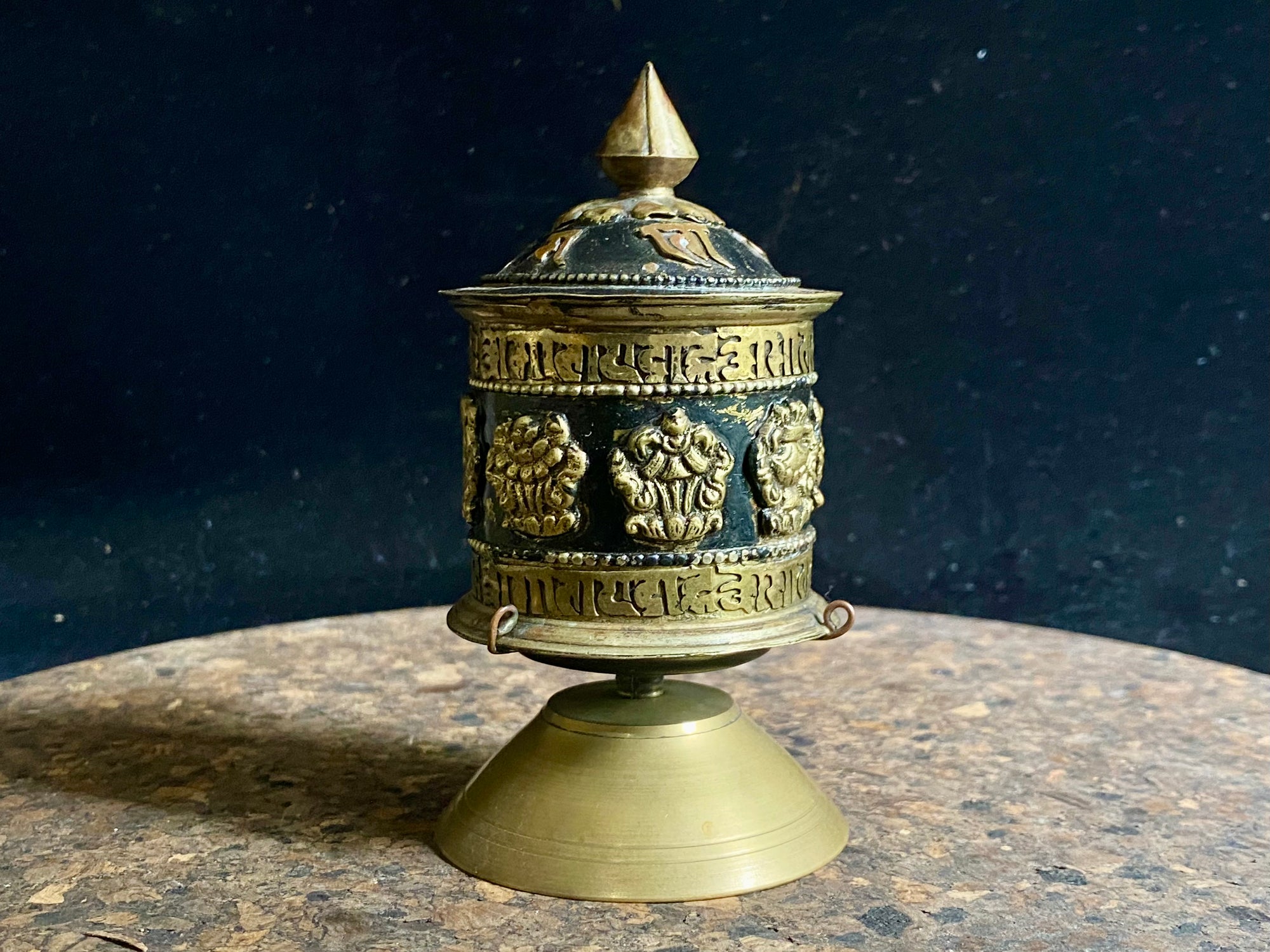 Standing prayer wheel, copper and brass, weighted for spinning and containing a scroll on which is printed the mantra "Om Mani Padme Hum", a prayer to the Compassionate Buddha, printed many times over. Measurements: height 12 cm, diameter 6.3 cm