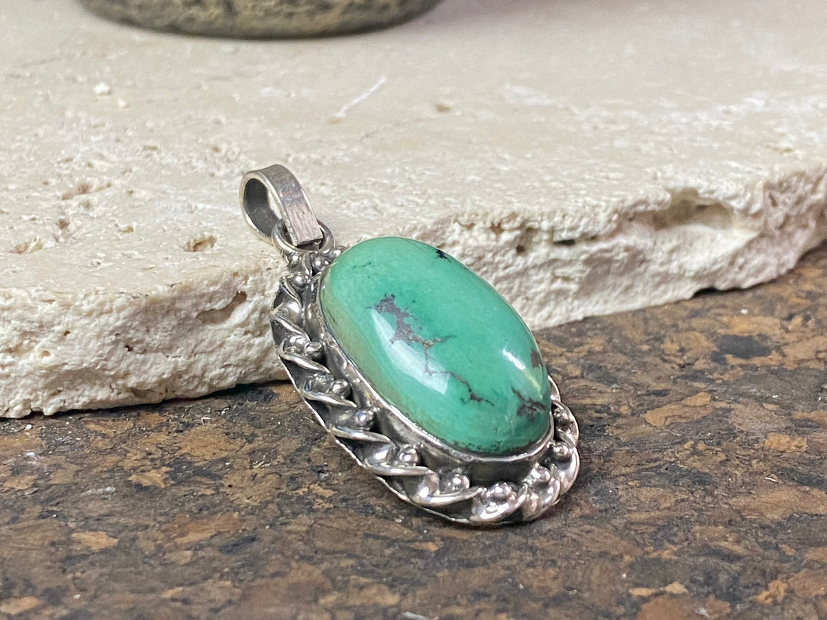 Arizona turquoise pendant set off by a detailed sterling silver bezel, with an enclosed silver back, topped by a large bail large. Measurements: 4.6 cm height including bail, width 2.2 cm