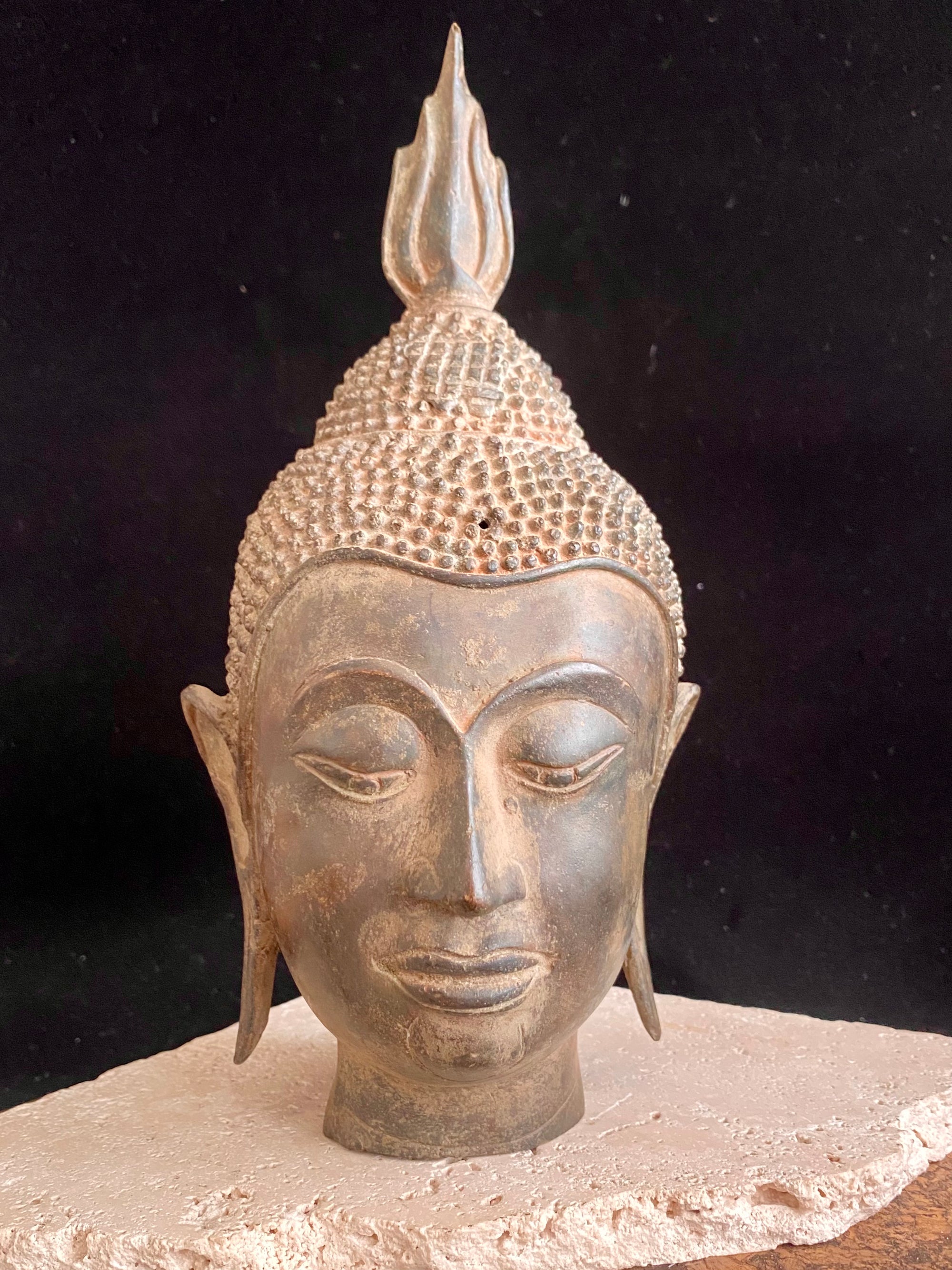 Thai Buddha head. Serene expression, hair topped with the flamed Ushnisha. Sukhothai style, bronze, mid 20th century. A softly contoured face with the bow shaped lips, prominent ears, arched eyebrows and aristocratic features typical of this style of work. Measurements: height 25 cm, width 11 cm