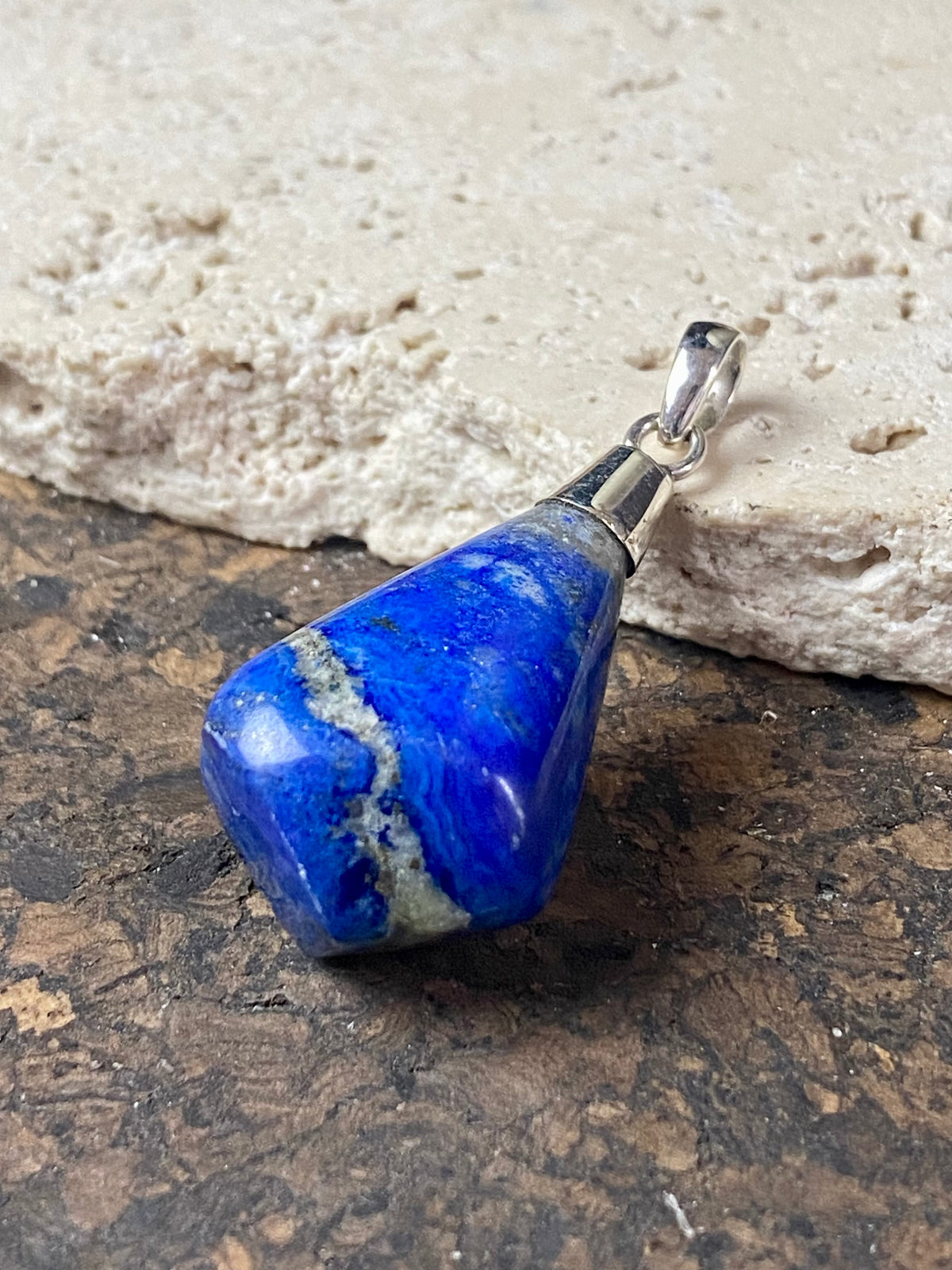 Freeform lapis lazuli top mounted pendant. The rich blue lapis originates from Afghanistan. Set in sterling silver with a generous bail to take a sizeable cord or chain. Height  5.5 cm