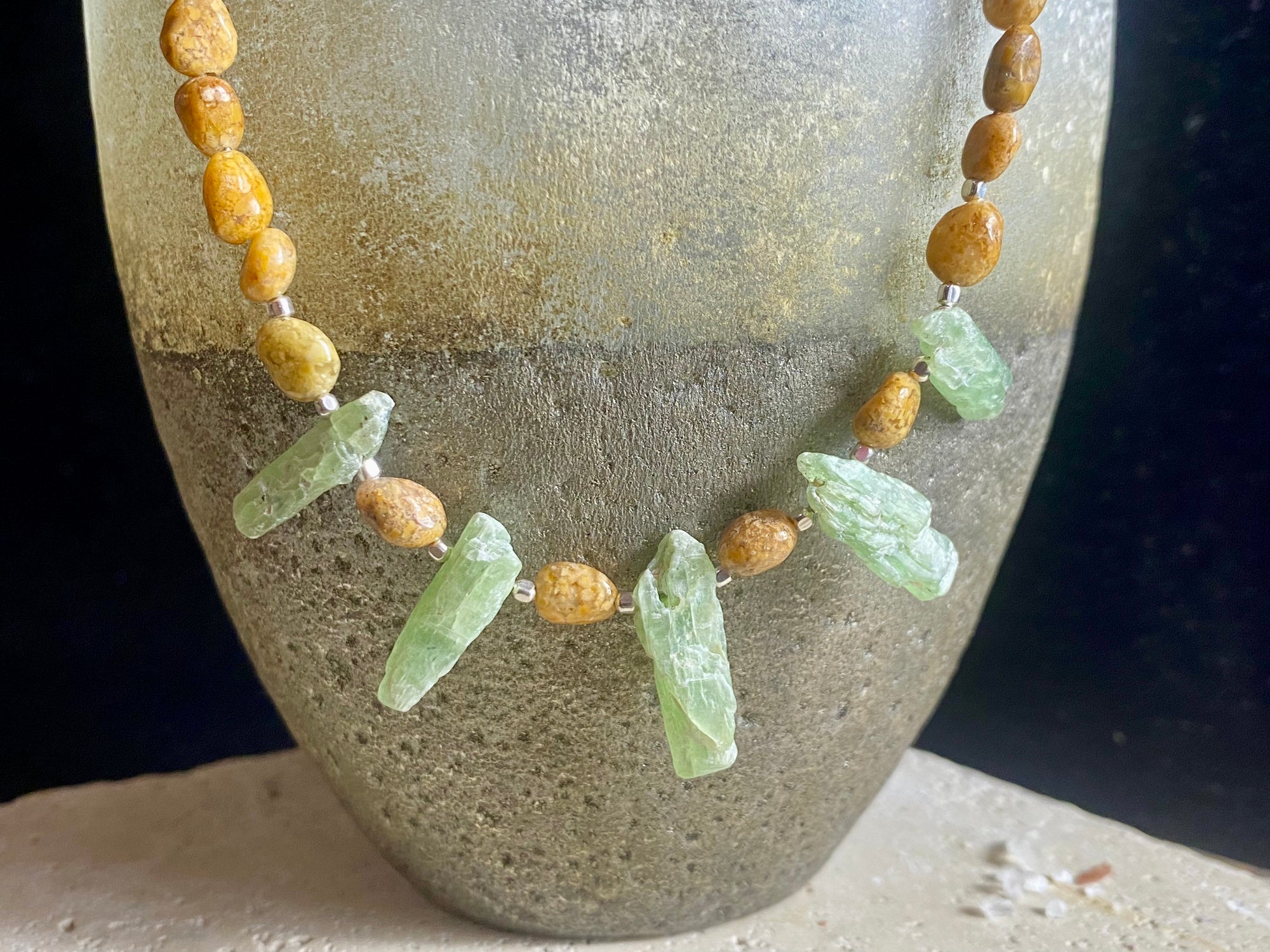 A polished pebble golden ocean jasper short necklace featuring spears of natural, unpolished green kyanite and sterling silver. Our necklace is finished with a sterling silver hook clasp and findings. Length 38 cm