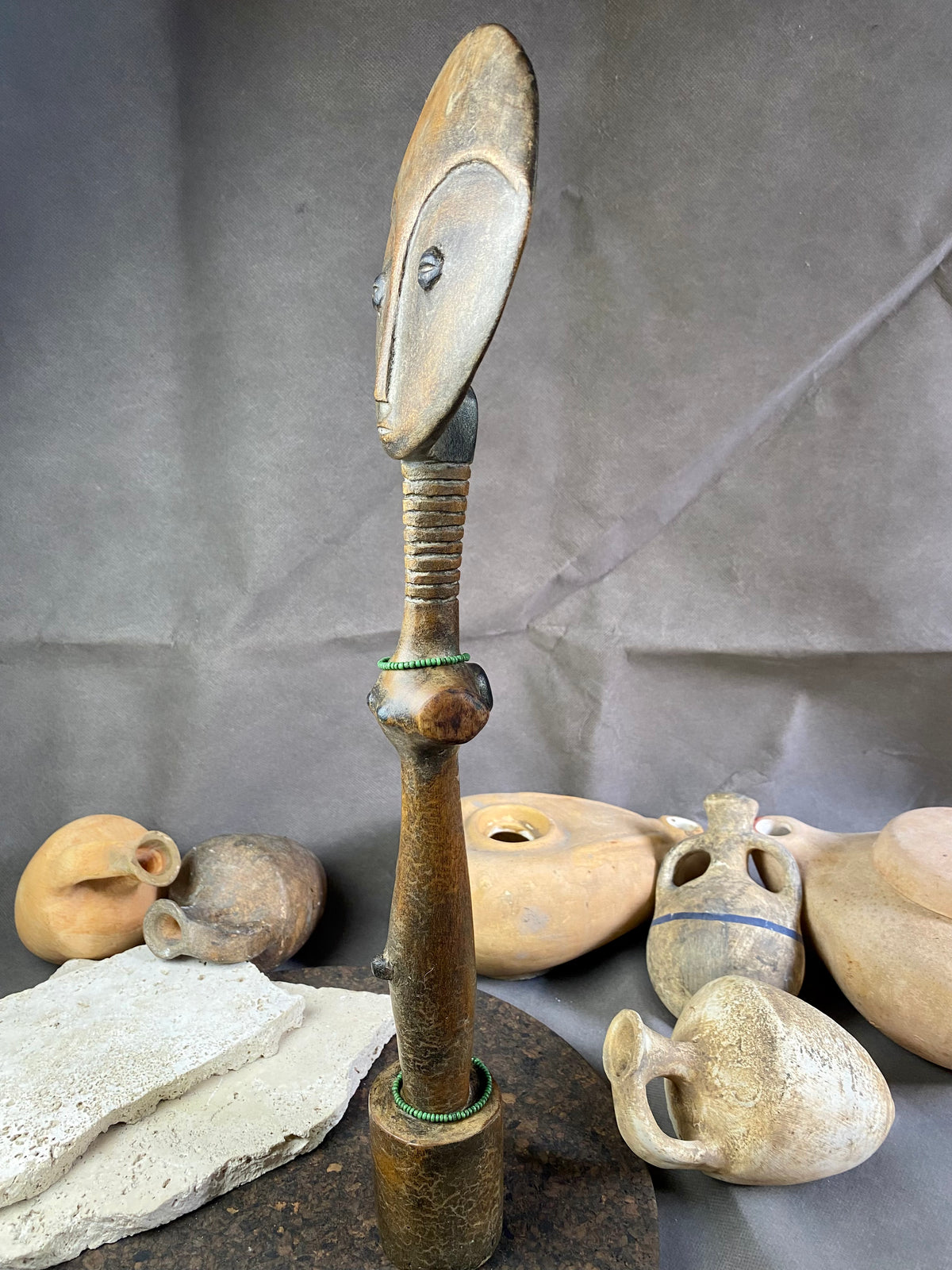 Late 20th Century vintage figure is carved from fine-grained wood, with a natural patina worn smooth with handling. She wears carved neck rings as well as beaded decoration, and a stylised pack on her back. This doll has an well carve face, with other features hinted at rather than explicitly carved. Height 43cm, width at head 11.5 cm.