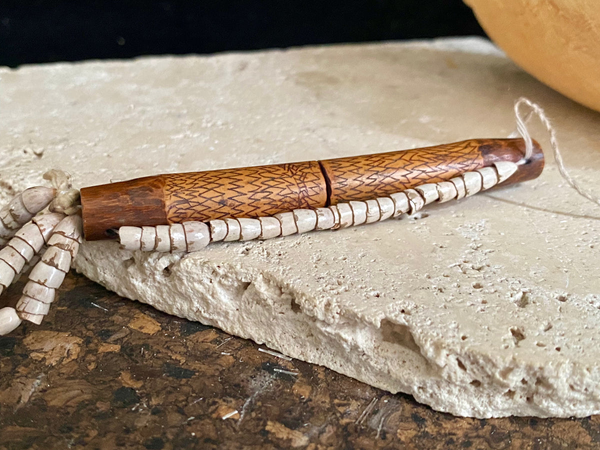 This is a vintage wood sewing needle case from northern Thailand, from the Ahka tribe. This beautiful, old and rare vintage piece is highly decorated and made from bamboo, etched, stained with red betel juice and finished with a long fringe of Jacob's tears. Length 24.5 cm with fringe, length of tube 9 cm