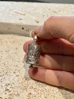 Miniature Buddhist prayer wheel pendant made from sterling silver, covered in images of the eight auspicious symbols and the mantra Om Mani Padme Hum. Prayer scroll inside.  Height 4 cm