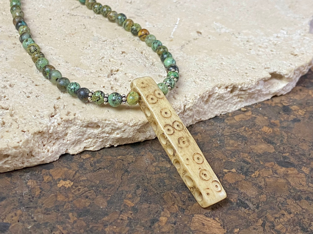 Tribal inspired necklace made from African jasper, highlighted with an antique Naga bone pendant and Kachin antique bone beads. Sterling silver findings and hook clasp. This unisex necklace is 45.5 cm (18") in length, pendant 5 cm (2") length.