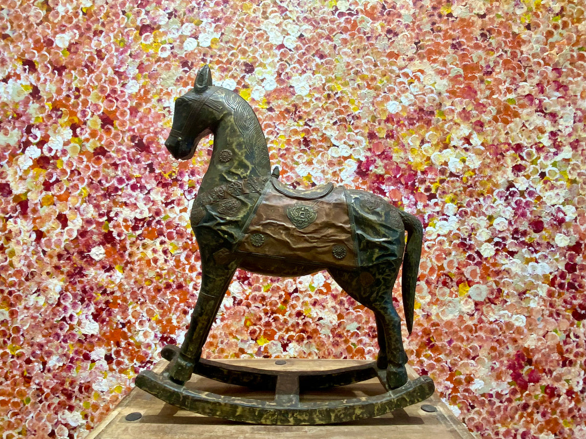 Antique Indian rocking horse. Covered entirely in sheets of embossed brass and copper sheet with floral and ornamental plaques, strap work and highly embossed decoration. Hardwood Early 20th century, southern India. Measurements: height to ear 52 cm, length 40.5 cm, width 13.5 cm.