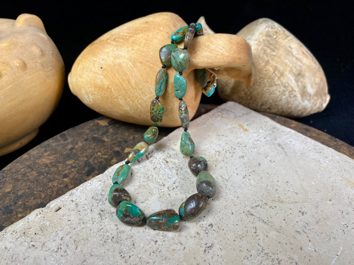 A necklace crafted from blue-green Tibetan turquoise, knotted between each bead in the traditional jewellery making technique of the region. Finished with sterling silver beads and hook clasp. Length 42 cm
