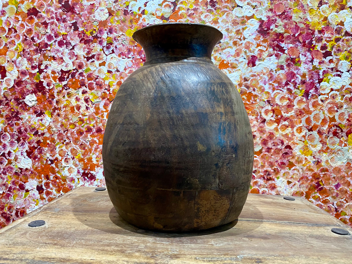 These gracefully shaped pots were used to store lassi, oil, milk, water and grain. This large example comes from northern India and is carved from solid hardwood, in this case most likely teak. Mid 20th century or earlier. slight decoration around the neck and mouth. Repair to the base. Measurements: diameter 22 cm, height 28 cm