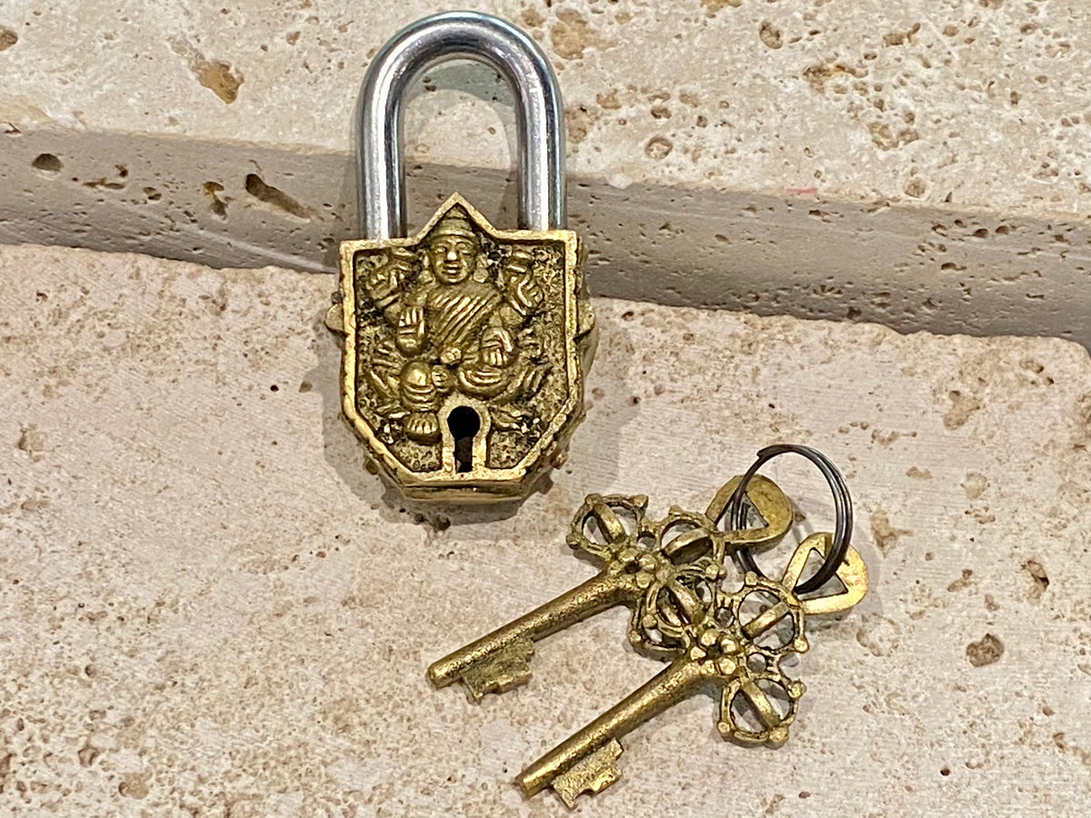 Small brass Indian deity padlocks embossed with the image of Ganesh or Laxmi. to keep your possessions safe and blessed. On the back is the Om, powerful Buddhist protective symbol. Two keys provided with every lock. On the top of each is the viswa vajra, a Buddhist protective symbol. Measurements: height 6.5 cm, width 3 cm, depth 1.5 cm
