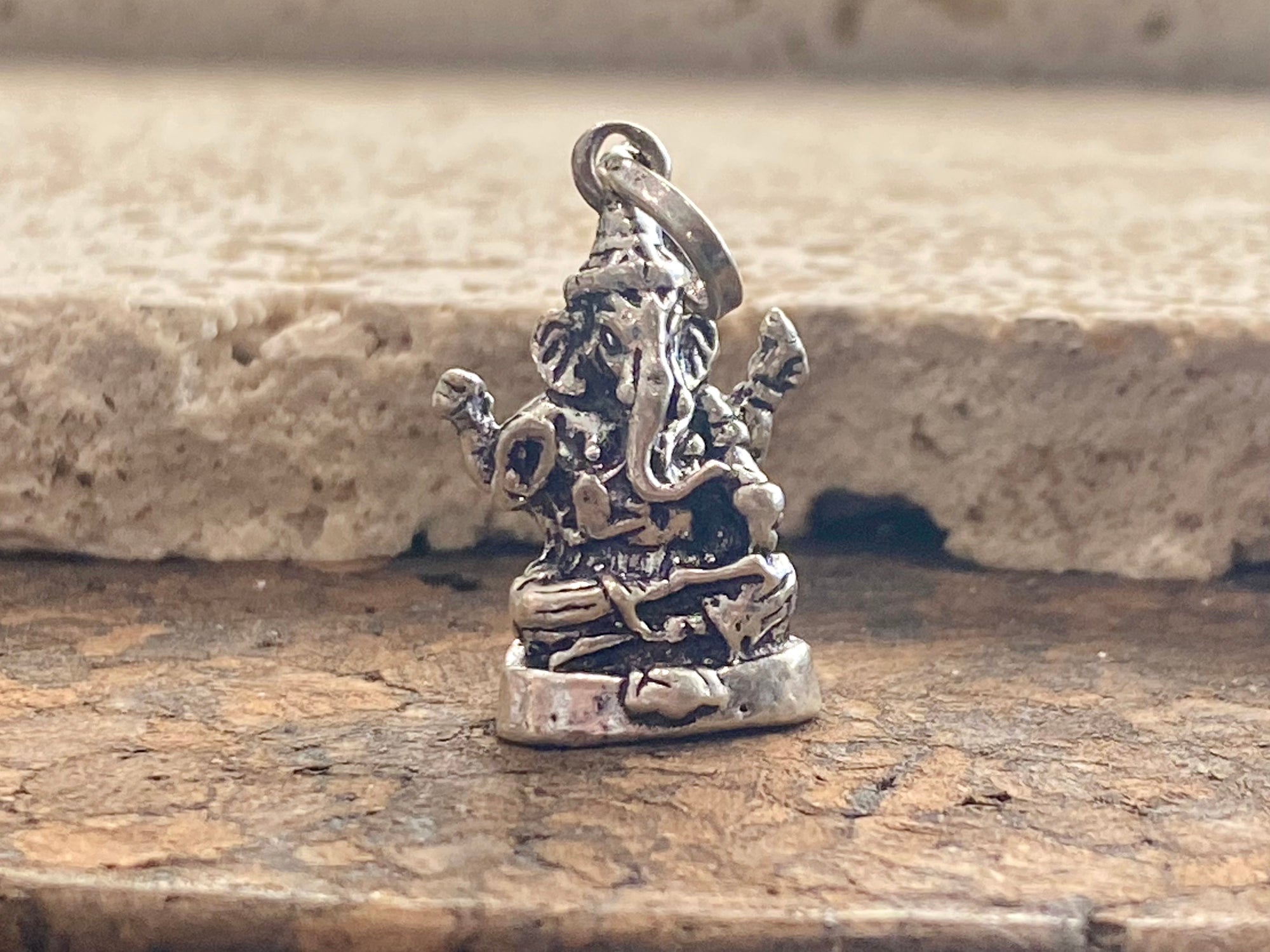 Sterling silver pendant featuring Lord Ganesha portrayed in 3D, this heavy silver charm pendant can be viewed in 3 dimensions, with his back as complete and as detailed as his front. A generous bail allows this pendant to be worn on a large chain or cord. he can even sit upright as the smallest of ganesh statues. This is a unisex pendant or statue. Sterling silver. Measurements: 3 cm height including bail