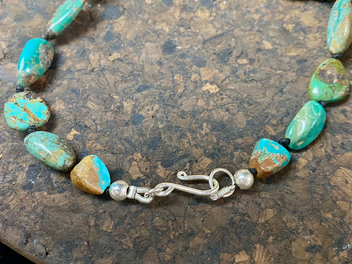 A necklace crafted from blue-green Tibetan turquoise, knotted between each bead in the traditional jewellery making technique of the region. Finished with sterling silver beads and hook clasp. Length 42 cm