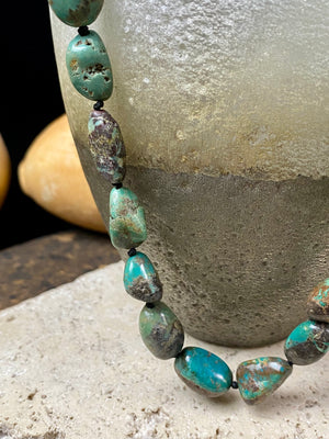 A necklace crafted from blue-green Tibetan turquoise, knotted between each bead in the traditional jewellery making technique of the region. Finished with sterling silver beads and hook clasp. Length 42 cm