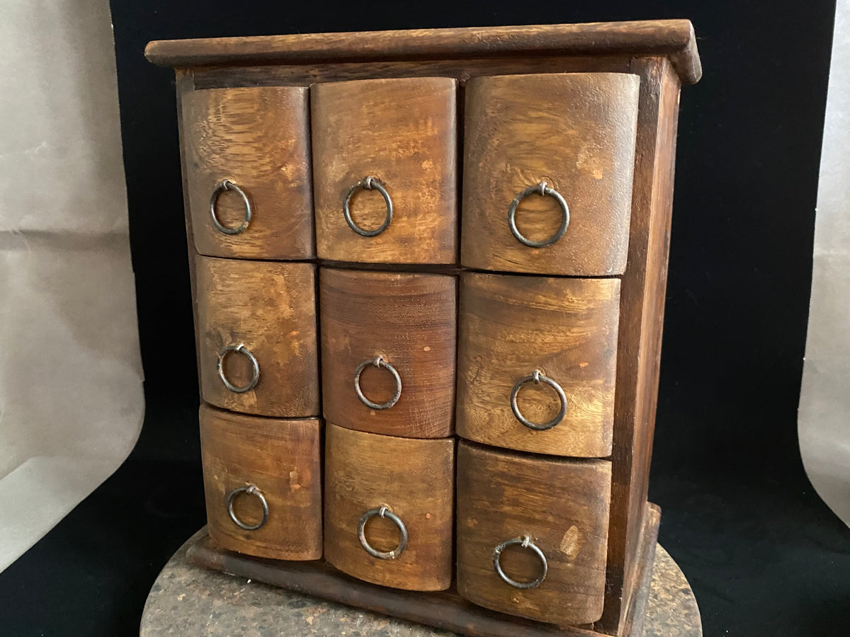 Simple curved face nine drawer cabinet trinket box. Made from solid Indian rosewood with iron rings as handles.  From Rajasthan, India. Made from Indian hard wood.  Height 28 cm, width 24.5 cm, depth 15.5 cm