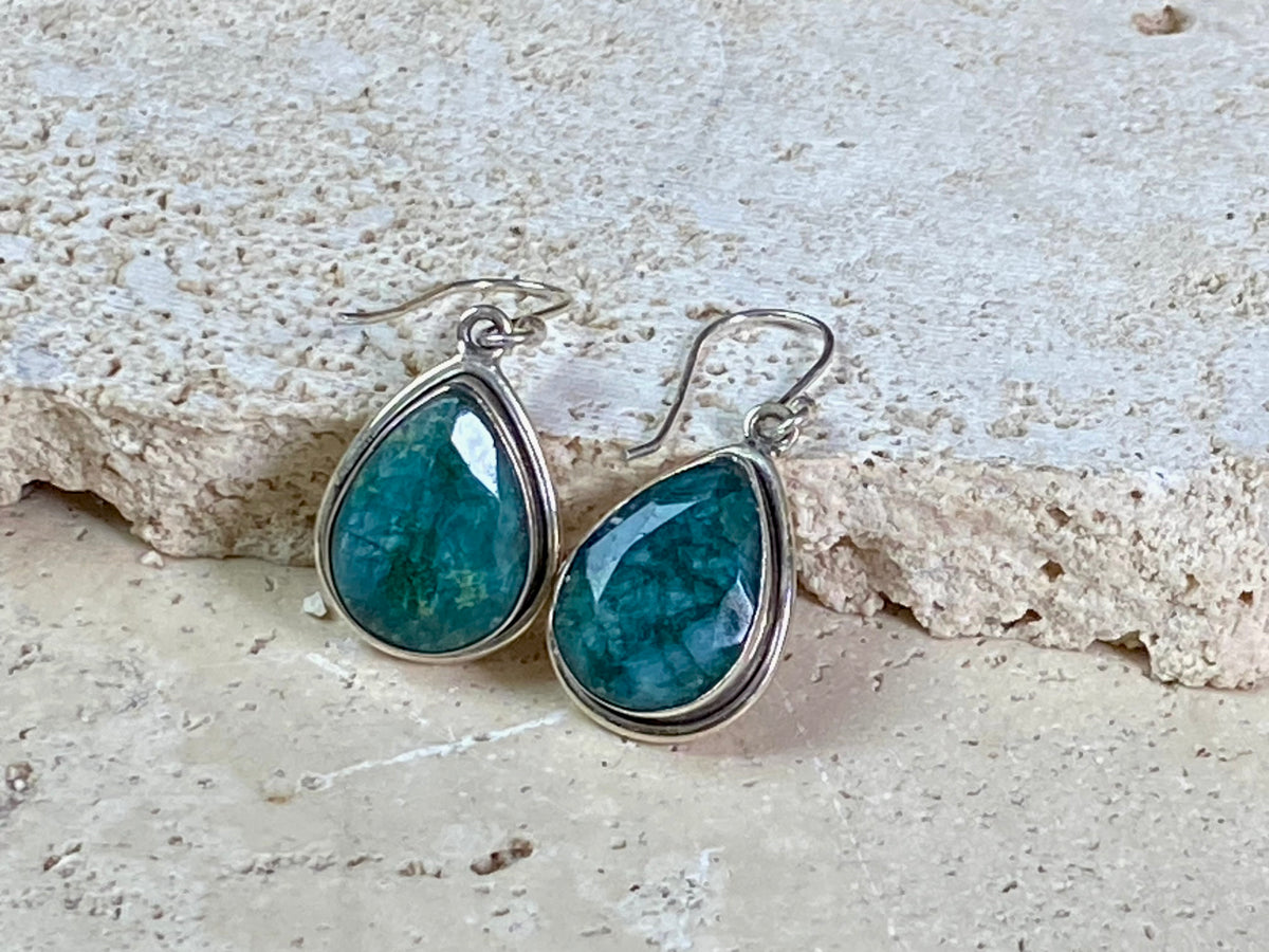 Our beautiful teardrop emerald earrings feature large facet cut emeralds of a deep variegated green colour. They are set in a sterling silver shadow box mount to highlight their beauty. measurements 3.6 cm length including hook.
